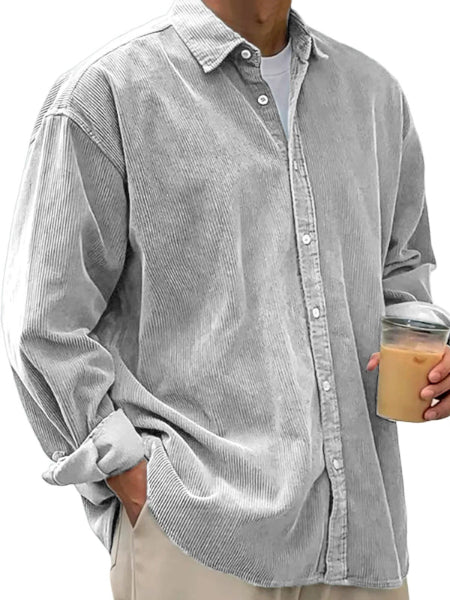 Person wearing a light gray corduroy shirt holding a drink.