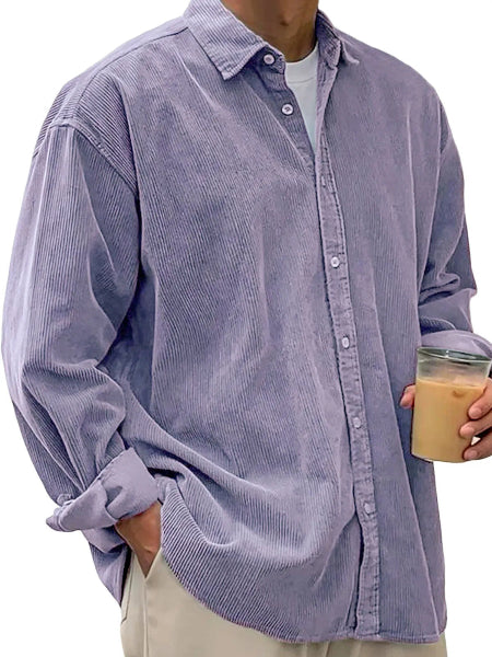 Person wearing a light purple corduroy shirt holding a coffee cup.