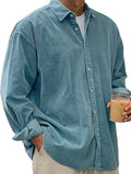 Person wearing a light blue corduroy shirt holding a drink.
