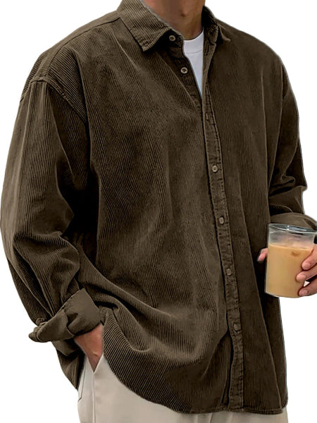 Person wearing a brown corduroy shirt holding a cup.
