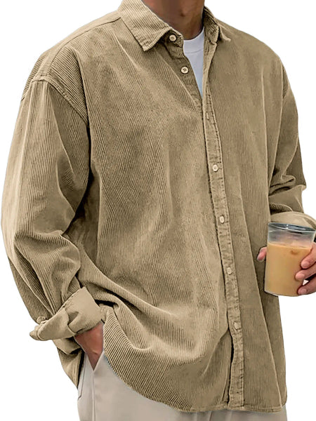Person wearing a beige corduroy shirt holding a coffee cup.